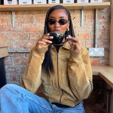  Influencer Rayan in blue jeans and a suede bomber jacket. 