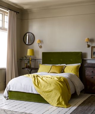 bedroom with green bed, yellow fabric and layered wall lighting with wall shades