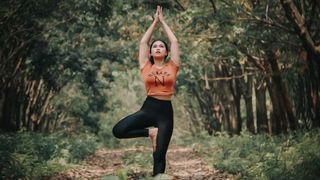 Woman doing tree pose in a forest