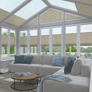 Living area in a large conservatory with cream coloured blinds and a corner sofa