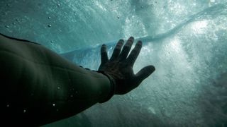 A hand reaching towards the surface of the water