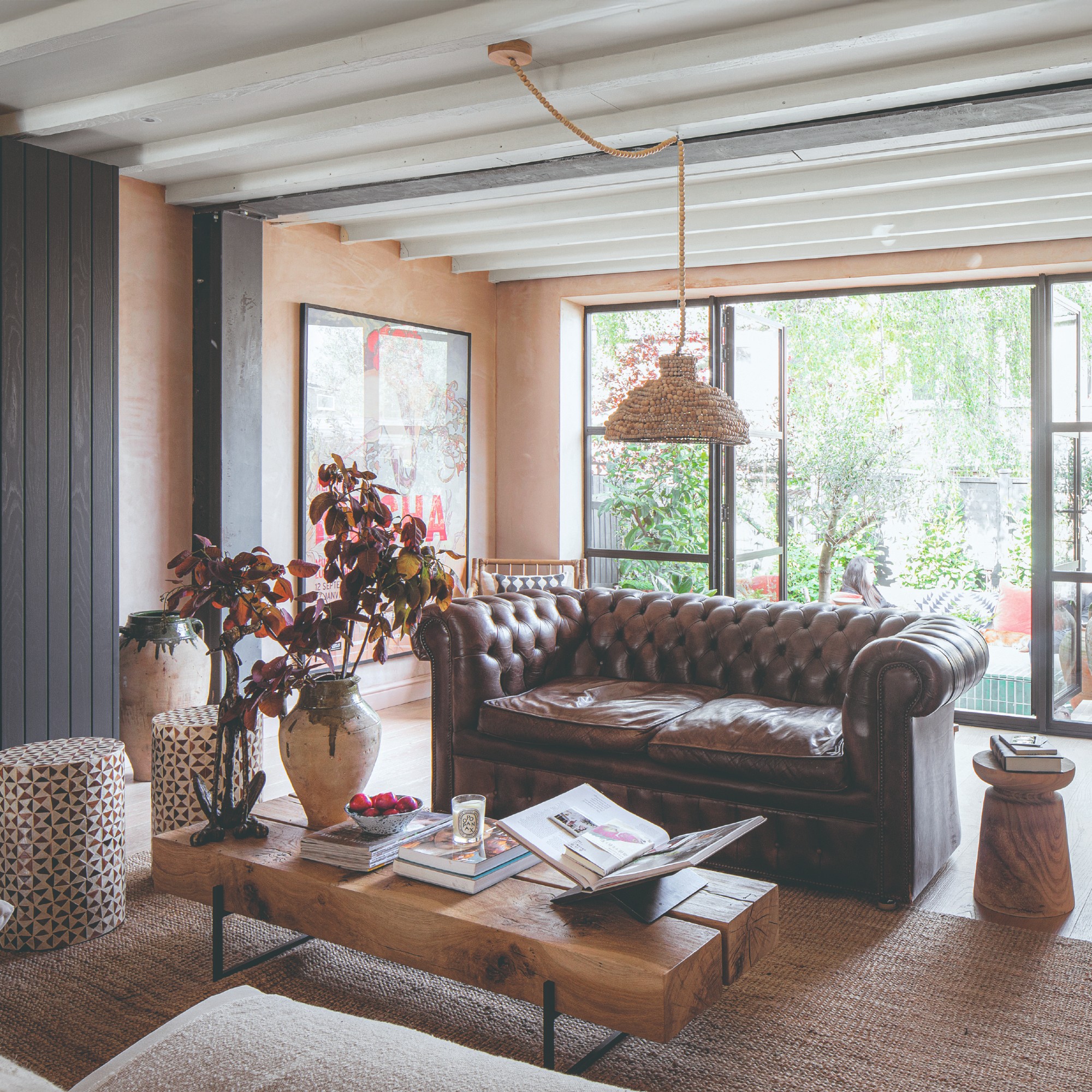 A pink-painted living room with a brown leather sofa and a coffee table made from a block of wood