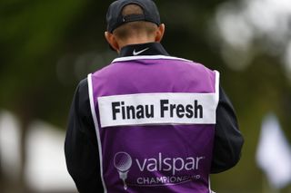 A caddie with Finau Fresh on the back of his bib