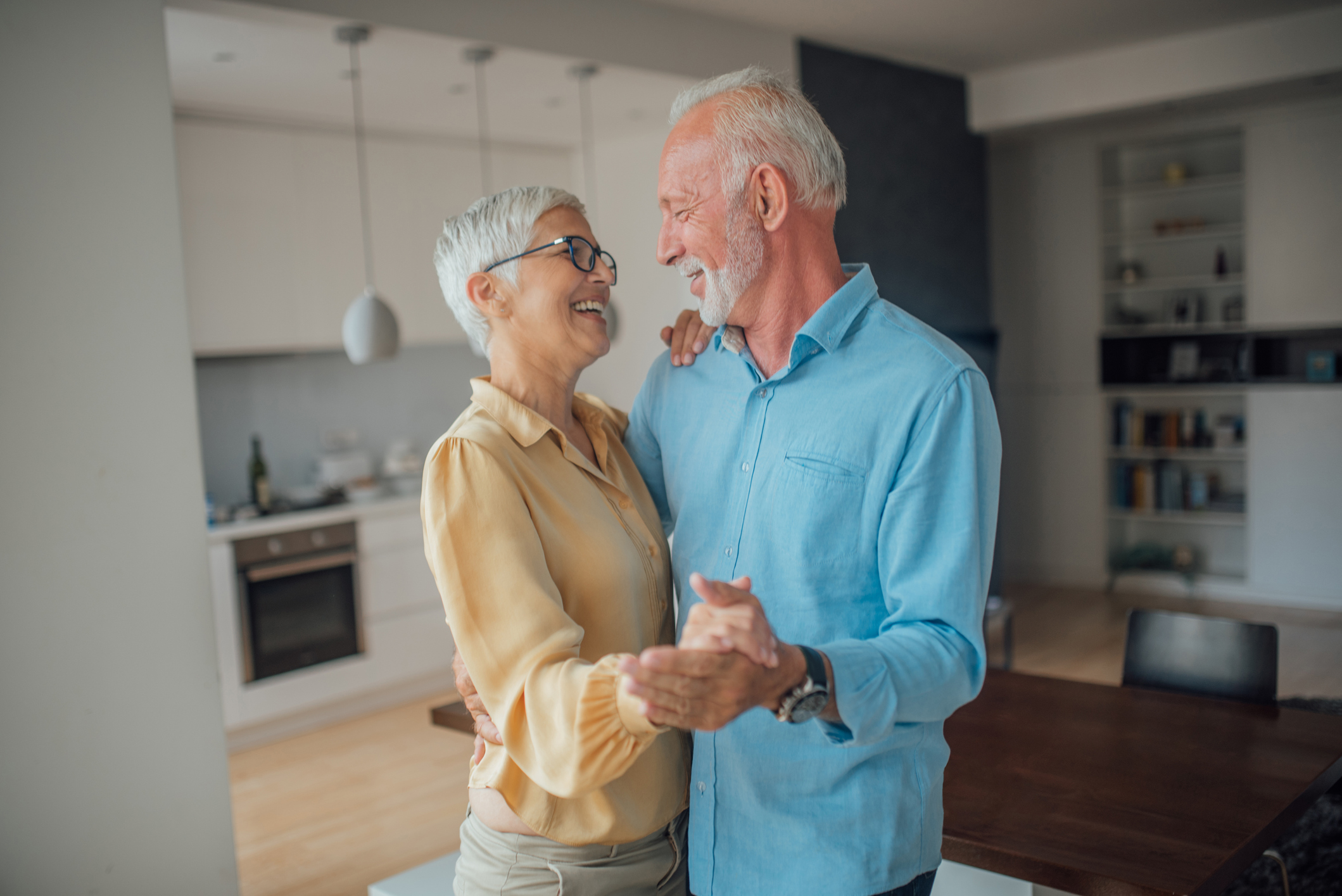 Romantic couple dancing at home and smiling while doing so.