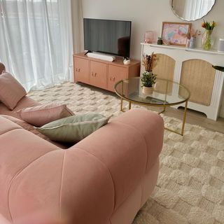 Pink couch facing TV focal point in modern living room with neutral area rug