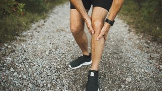 a photo of a runner clutching his knee 