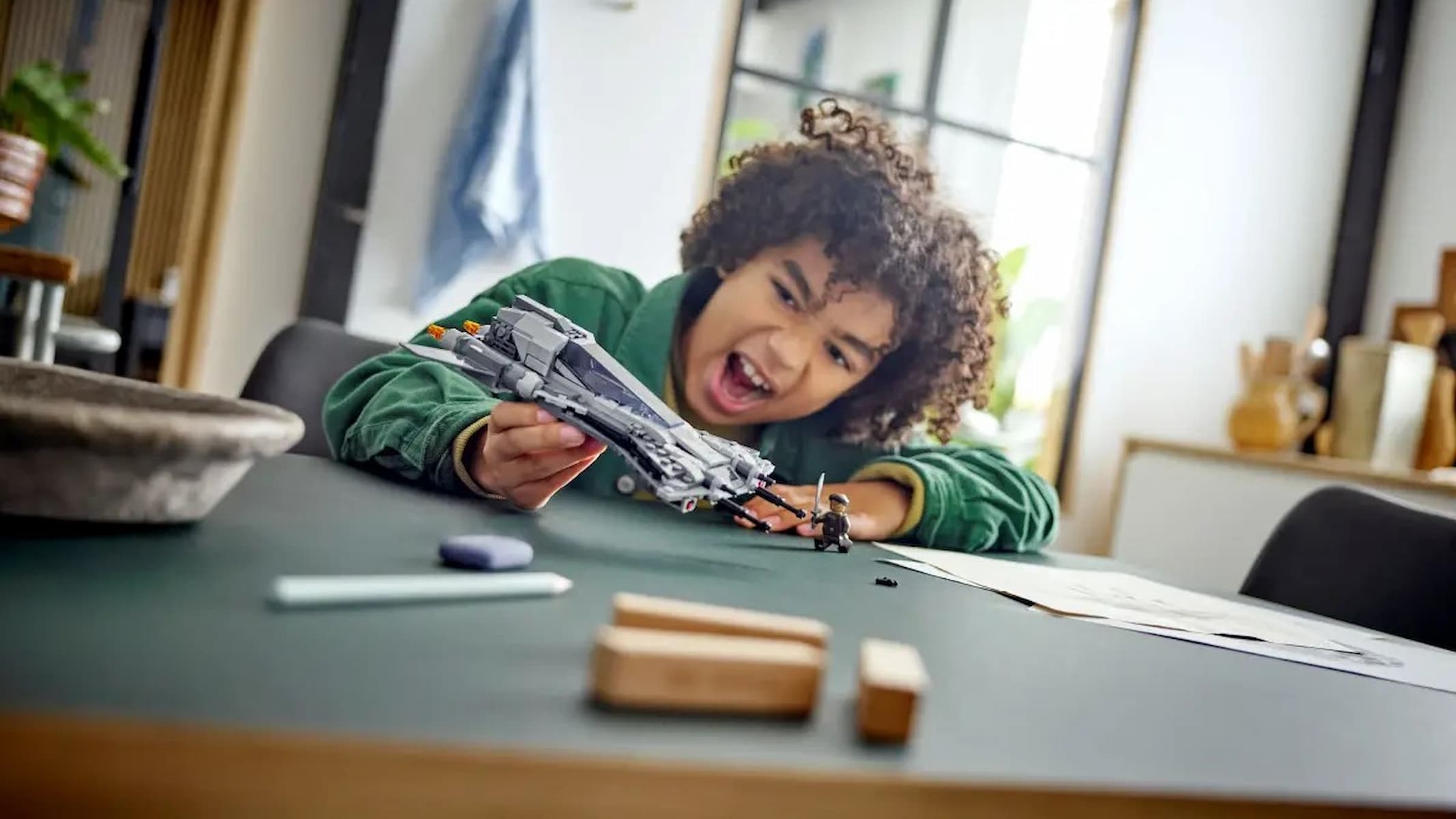 A young boy playing with the Lego Star Wars Pirate Snub Fighter set.