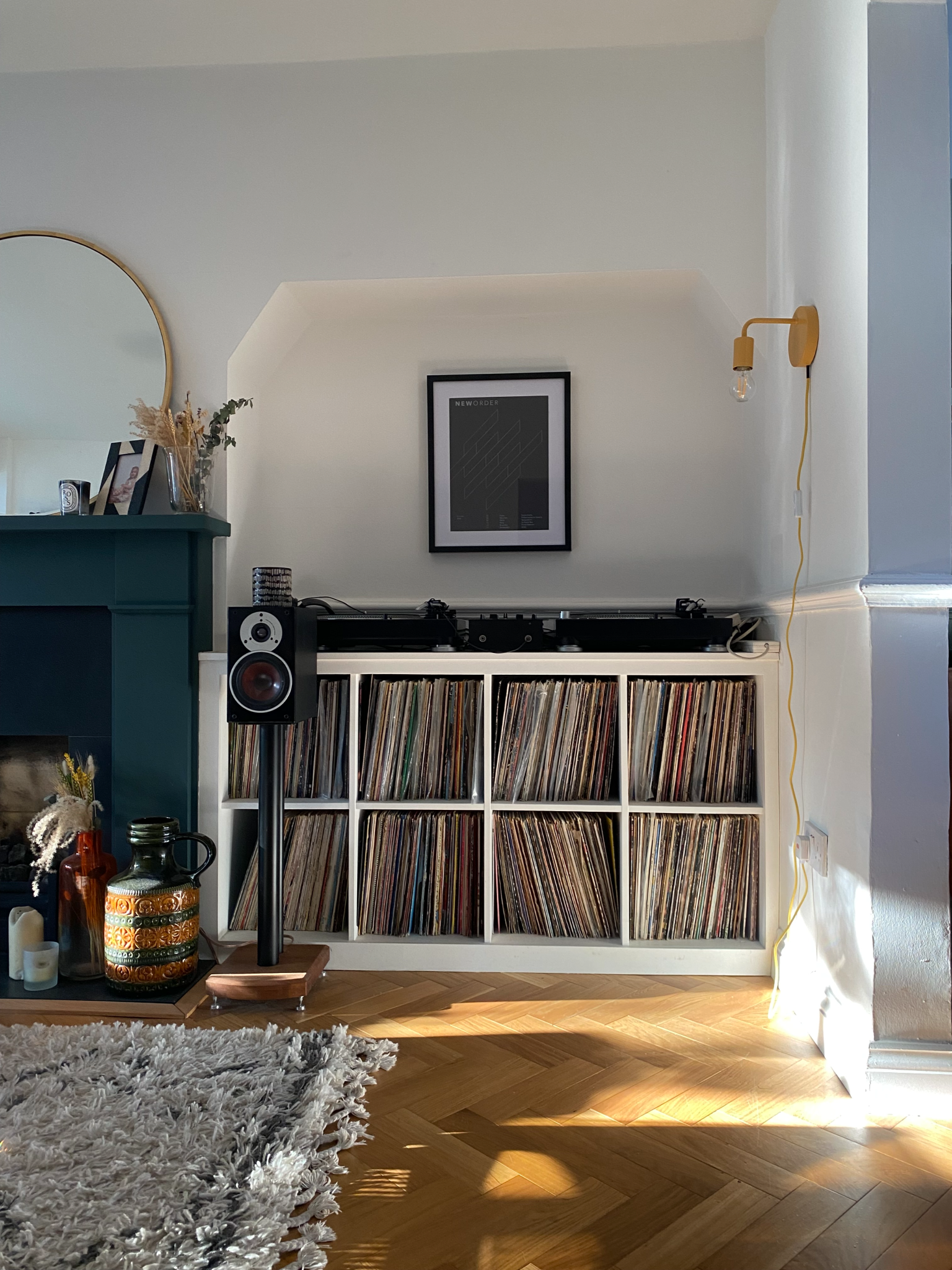A living space with a record shelving unit in an alcove with DJ decks on the tabletop