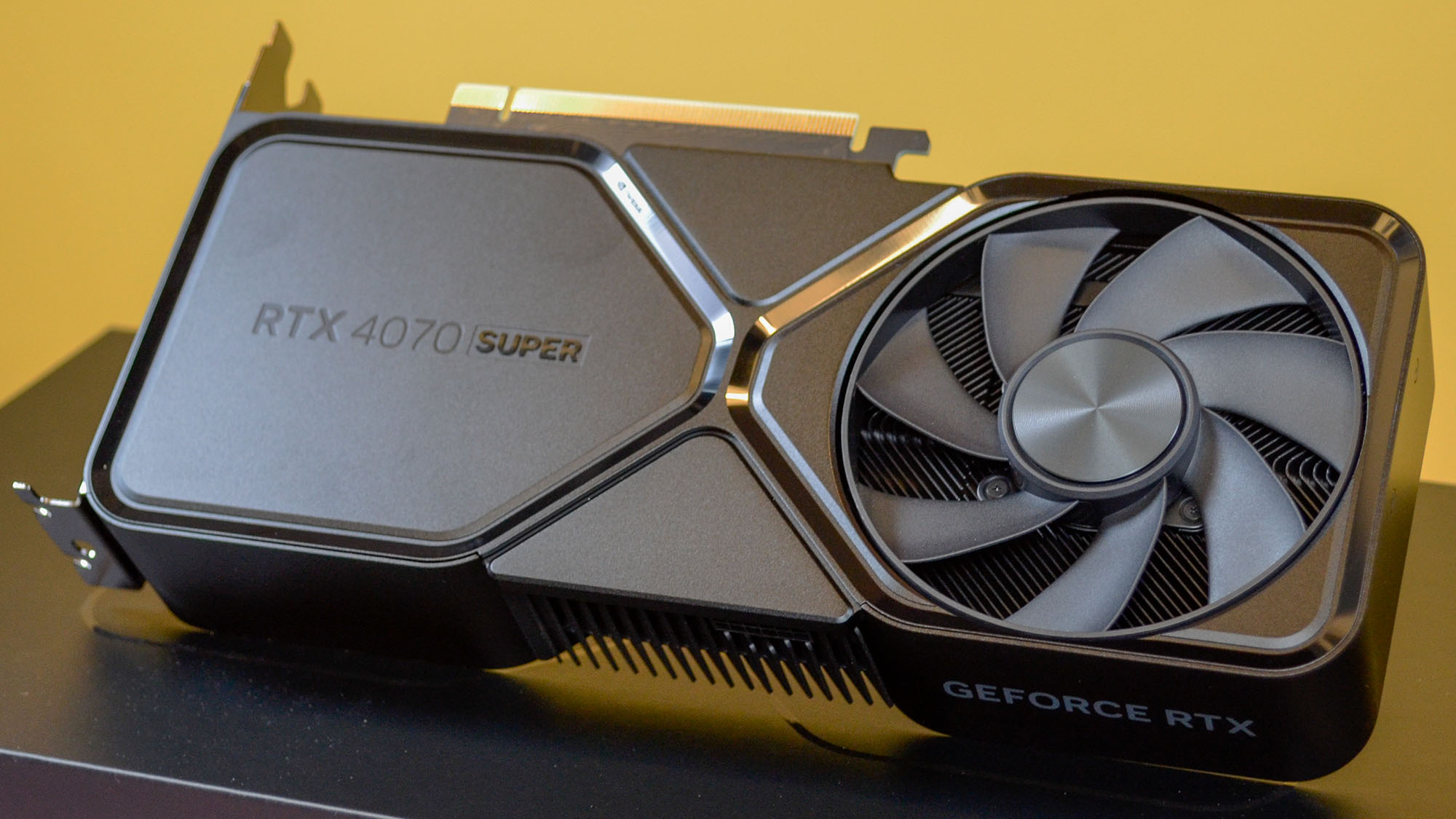 An Nvidia GeForce RTX 4070 Super on a desk in front of a yellow background