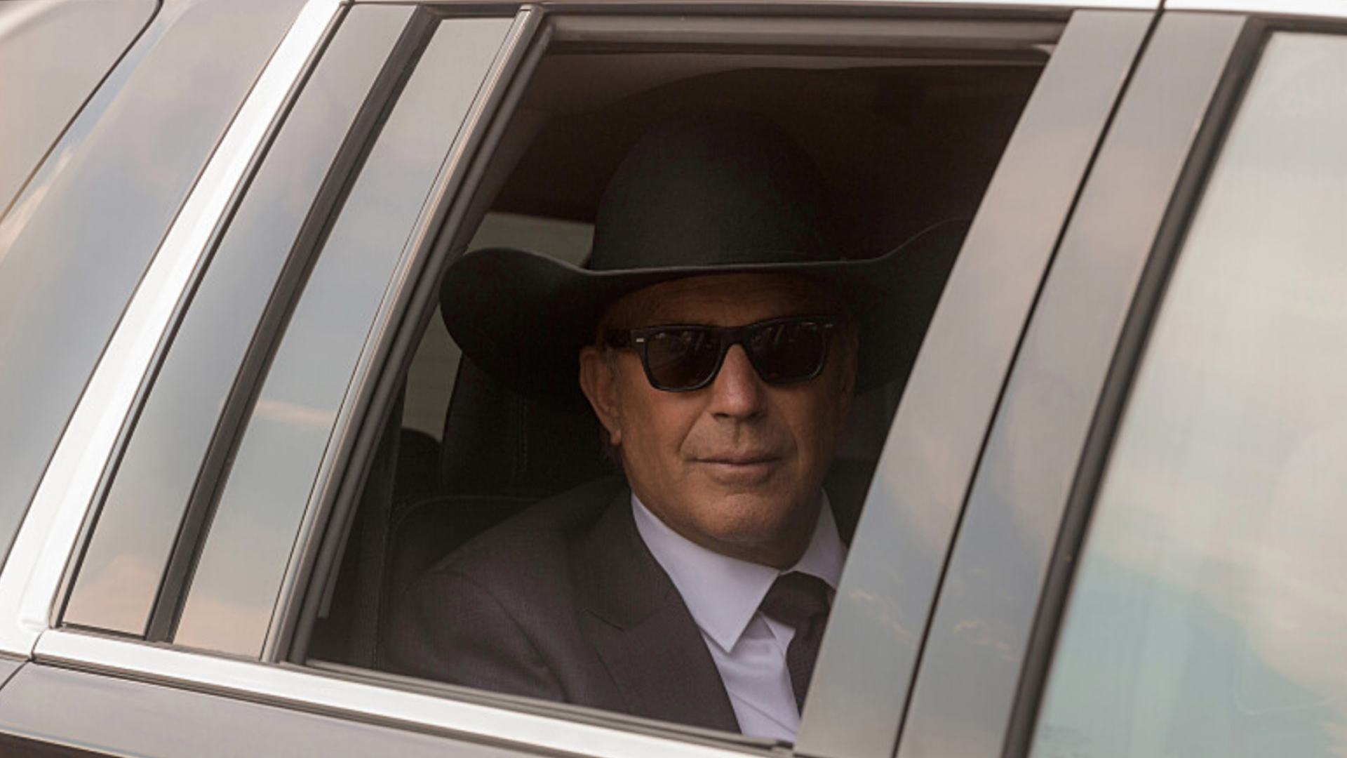 Kevin Costner in a limo with a large cowboy hat on