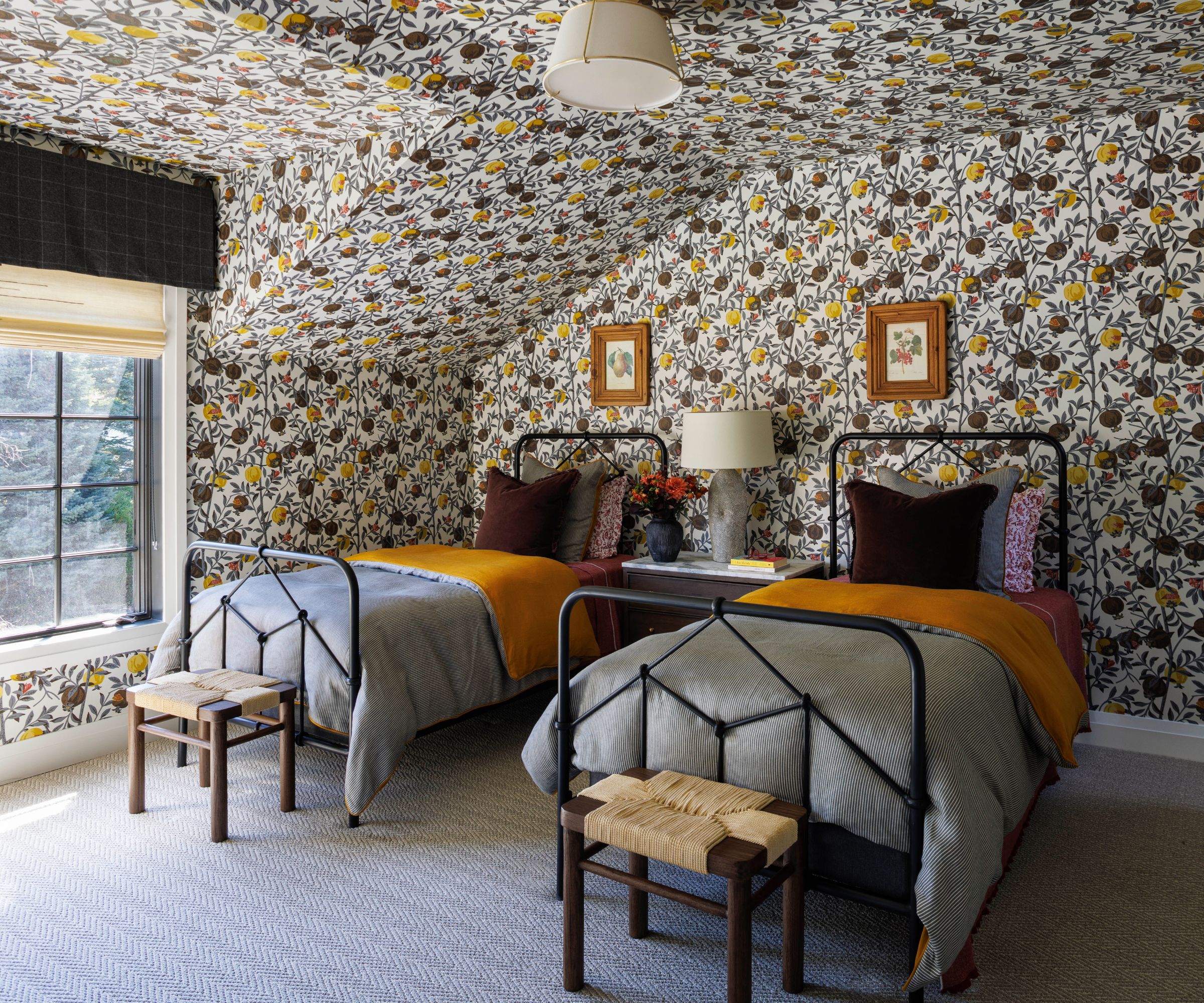 Twin bedroom with floral wall print over the walls and ceiling, two black iron beds with great and yellow bedding