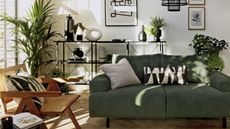 Green sofa in a modern boho living room with black display shelves and a rattan chair from Habitat