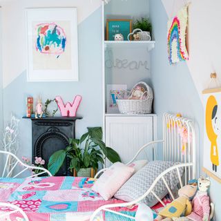 Blue girls bedroom with white bedframe, blue painted shape, built-in storage and fireplace