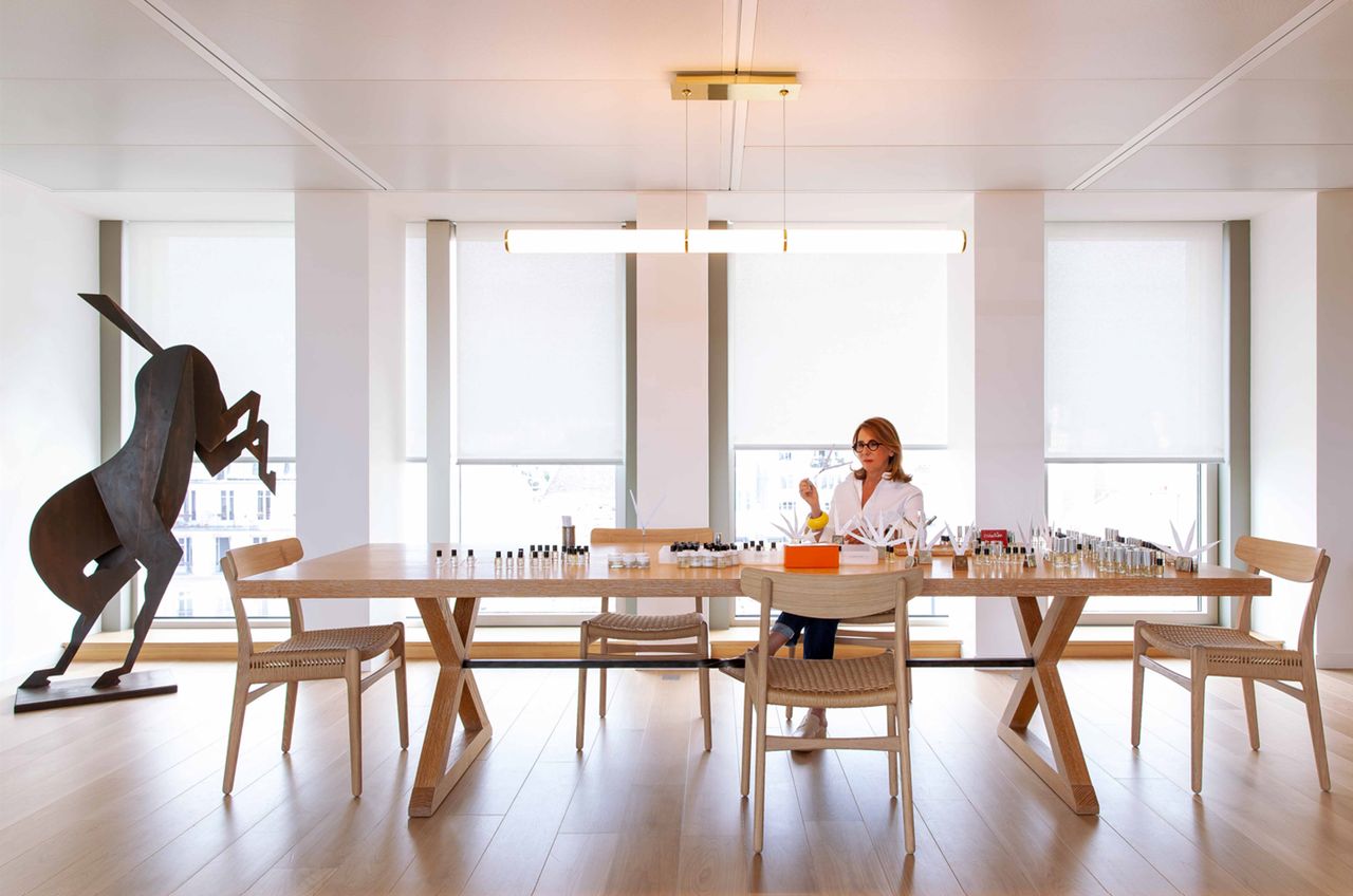 Hermès in-house nose Christine Nagel in her perfume lab with Hermès Oud Alezan perfume bottles, and bucking horse sculpture