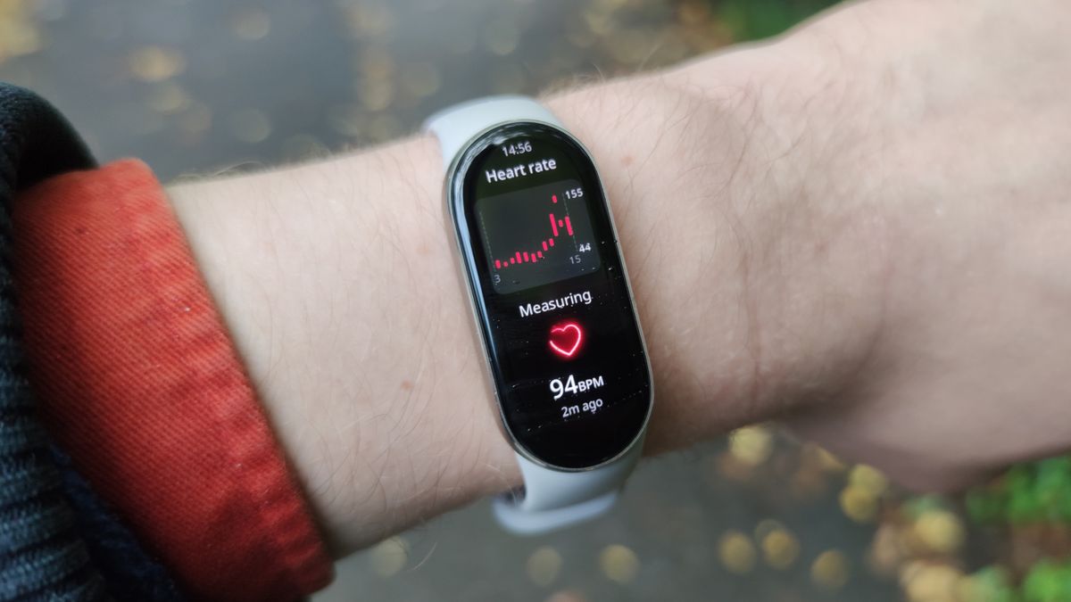 The Xiaomi Smart Band 9 on a man&#039;s wrist in front of a green park.