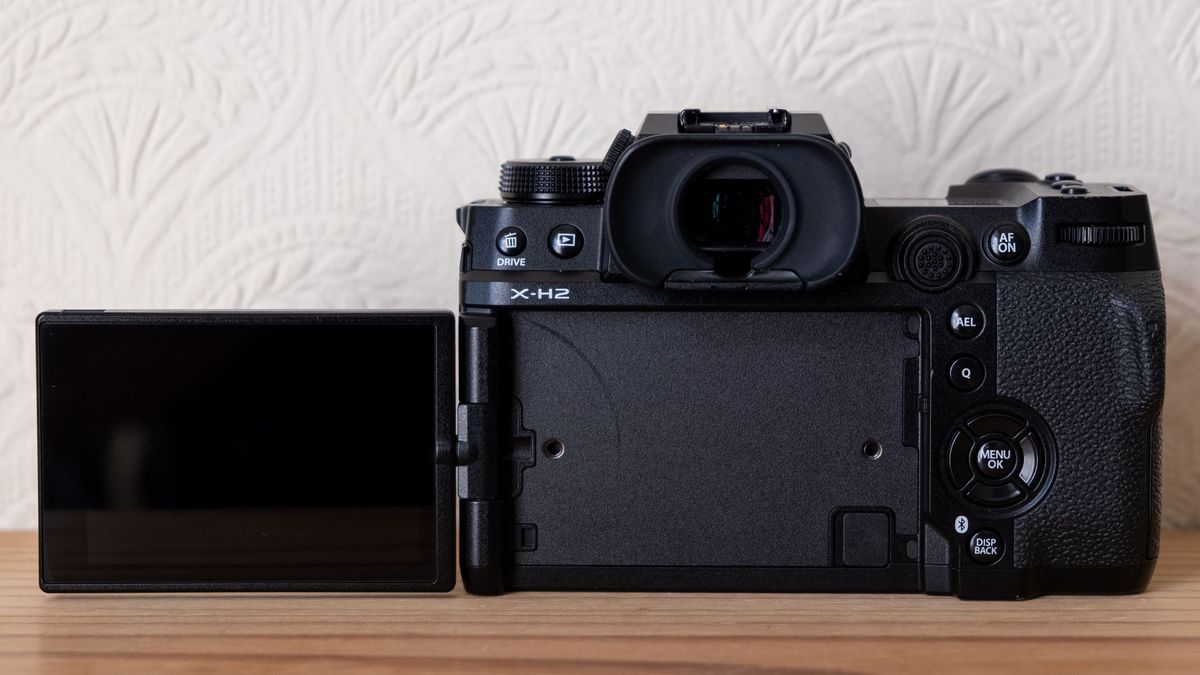 The Fujifilm X-H2 from the back with screen flipped out to the left.