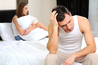 Upset man having problem sitting on the bed with his girlfriend.