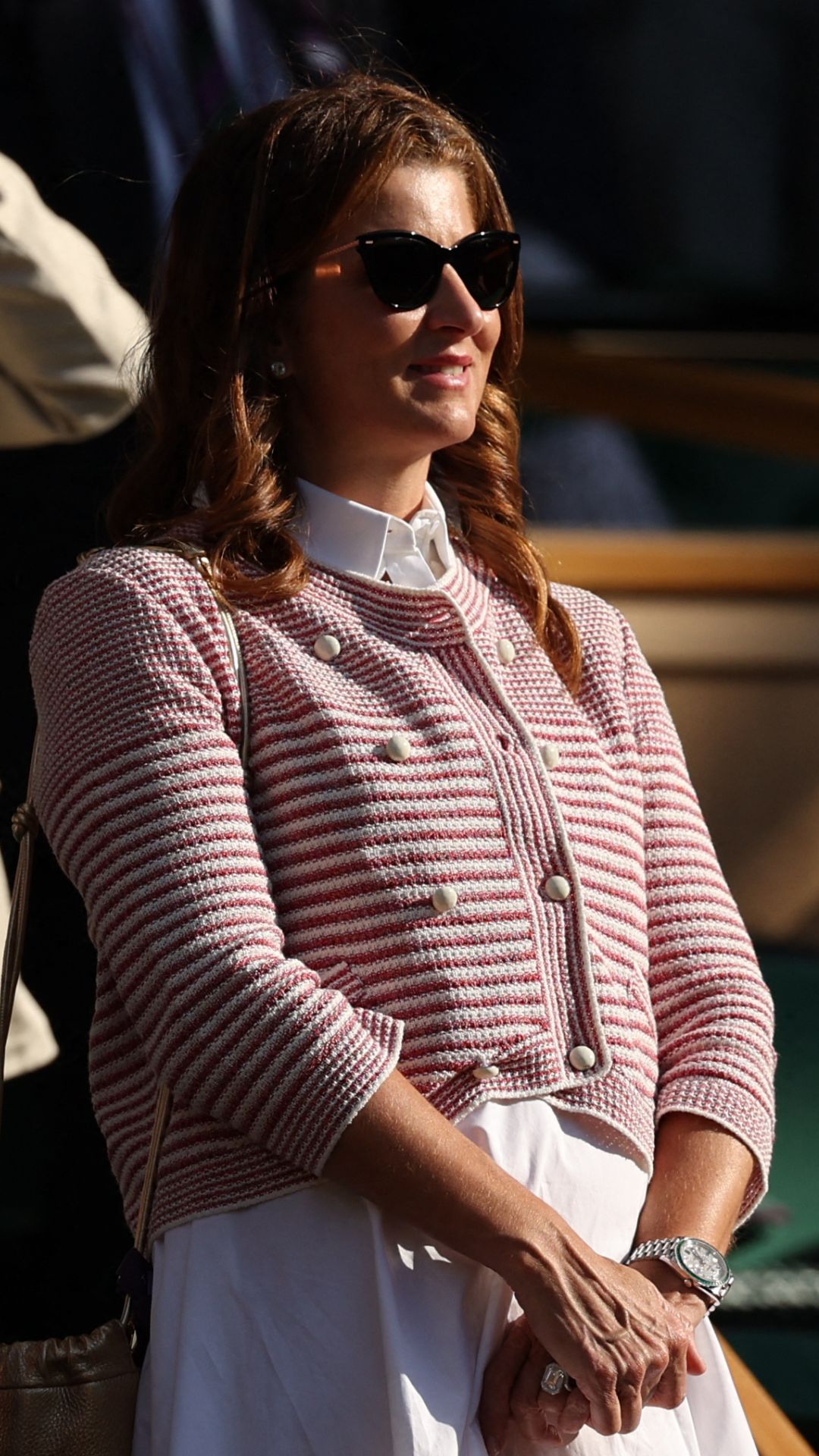 Mirka Federer wearing white Valentino midi dress and pink and white stripe cardigan at Wimbledon 2025 on July 07, 2025 in London, England