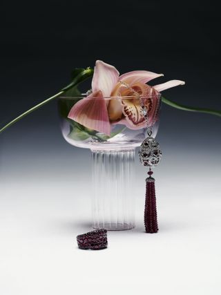 Fabergé necklace displayed on a glass with a flower