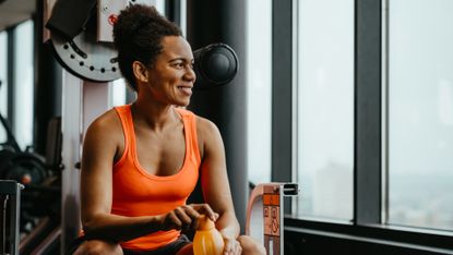 Woman relaxing in gym and holding a water bottle