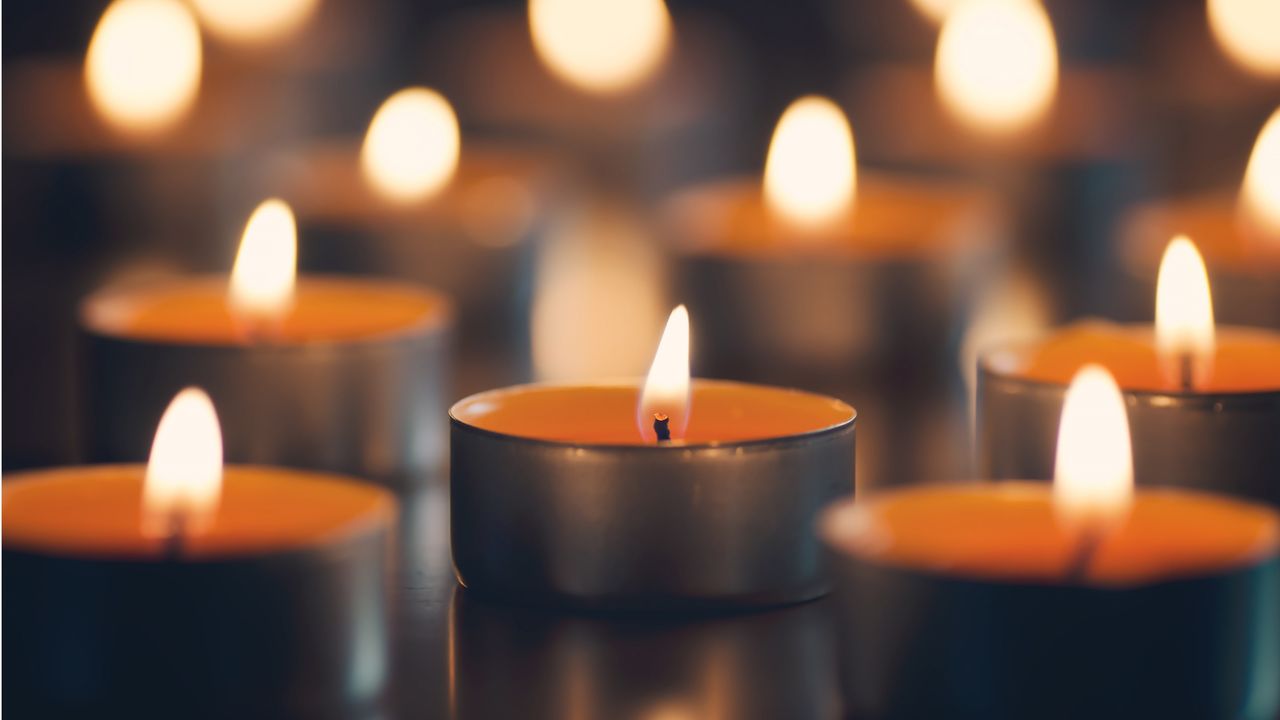 A group of candles like those found in a church are lighted.