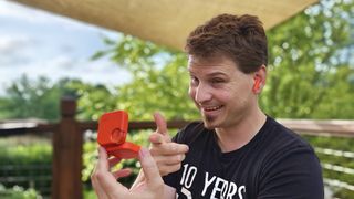 Wearing an orange CMF Buds 2 earbud and holding the case