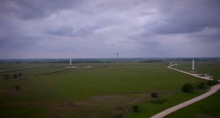 A SpaceX Falcon 9 Reusable rocket prototype (left) and the firm's smaller Grasshopper test bed (far right) are seen atop their test pads in McGregor, Texas.