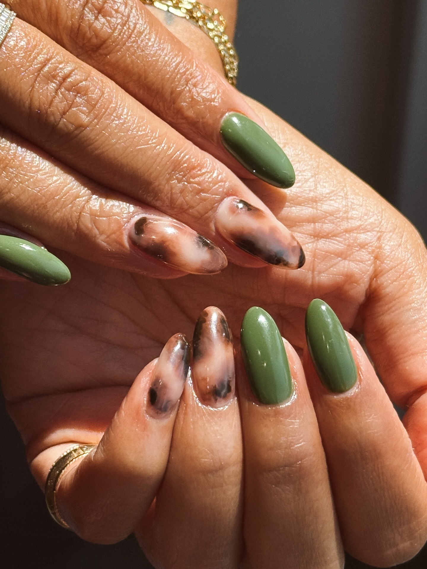 An earthy green manicure with brown nail art