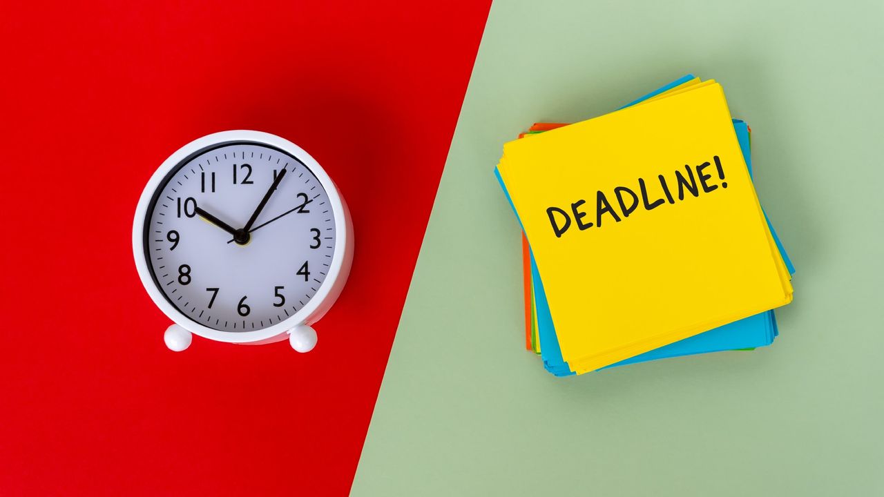 Clock and a sticky note that reads &quot;Deadline!&quot; on a green and red background