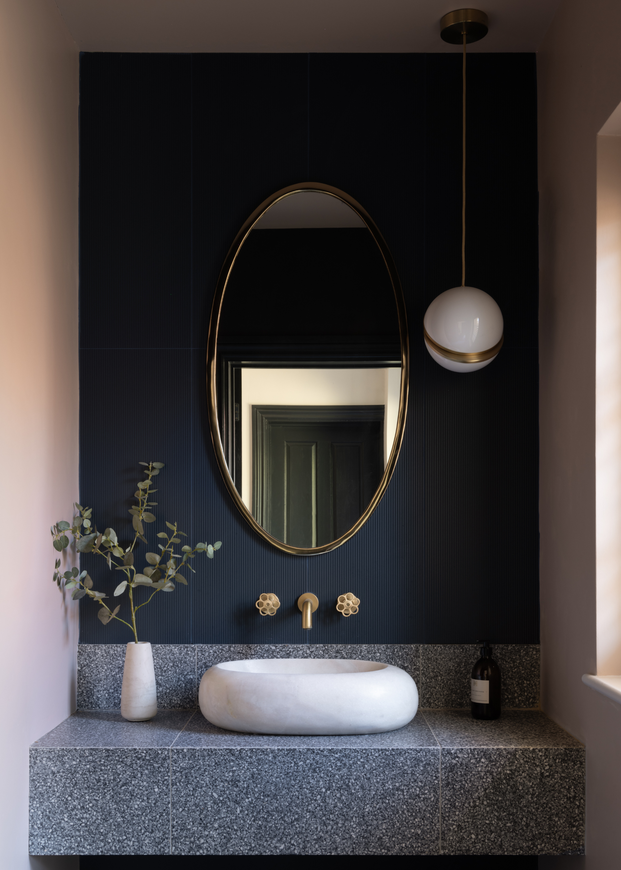 bathroom sink area with terrazzo counter and backsplash