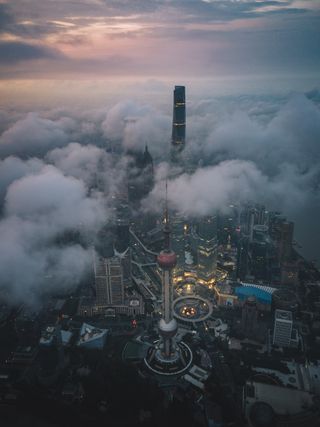 An aerial view of a city skyline emerging from under clouds