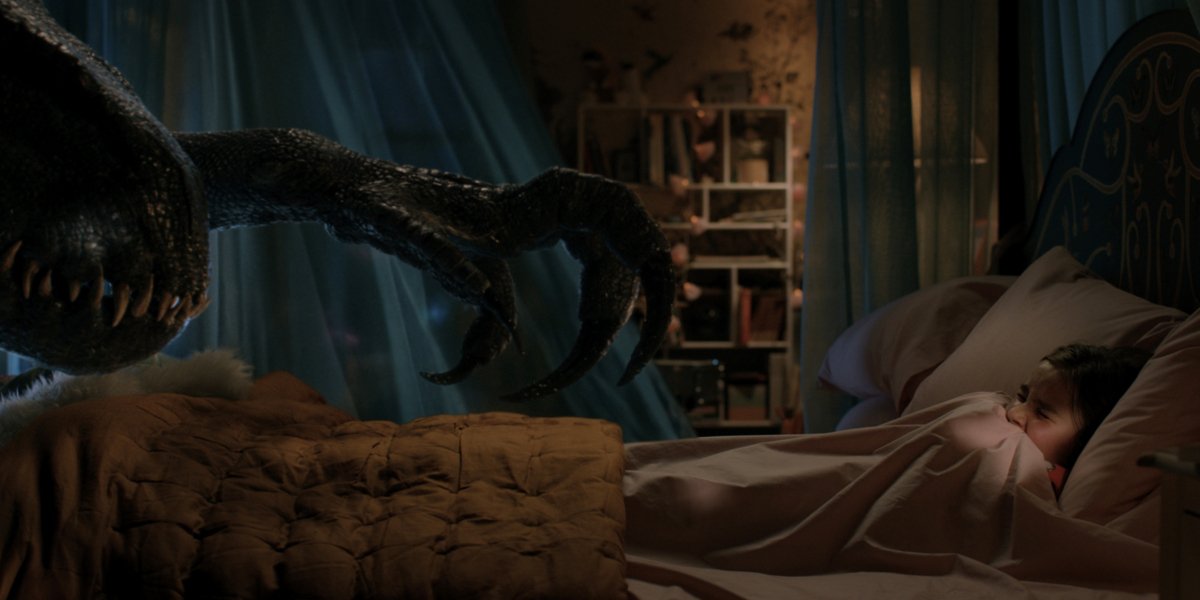 The Indoraptor reaches towards a frightened Isabella Sermon in Jurassic World: Fallen Kingdom.