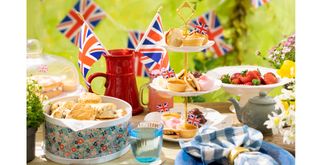 Coronation decorations on a party table with cake stands and union Jack flags