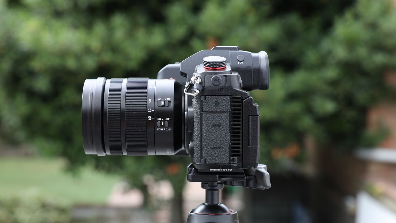 Panasonic Lumix GH7 on a tripod outside with some blurred green trees in the background