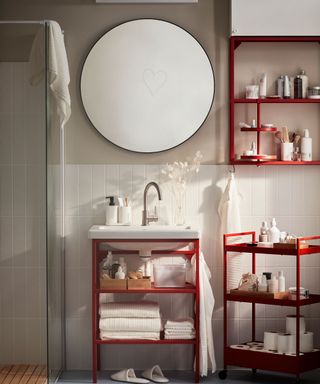 Mirror in bathroom with red storage shelving and clear shower door