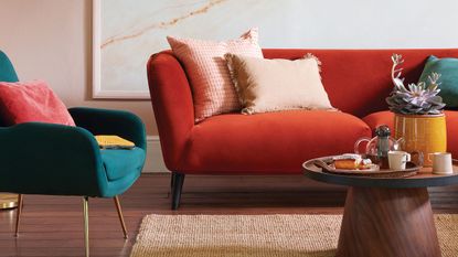 orange velvet sofa with plaster pink cushions in a pink room with dark wood floor