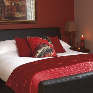 bedroom with side table and red cushions