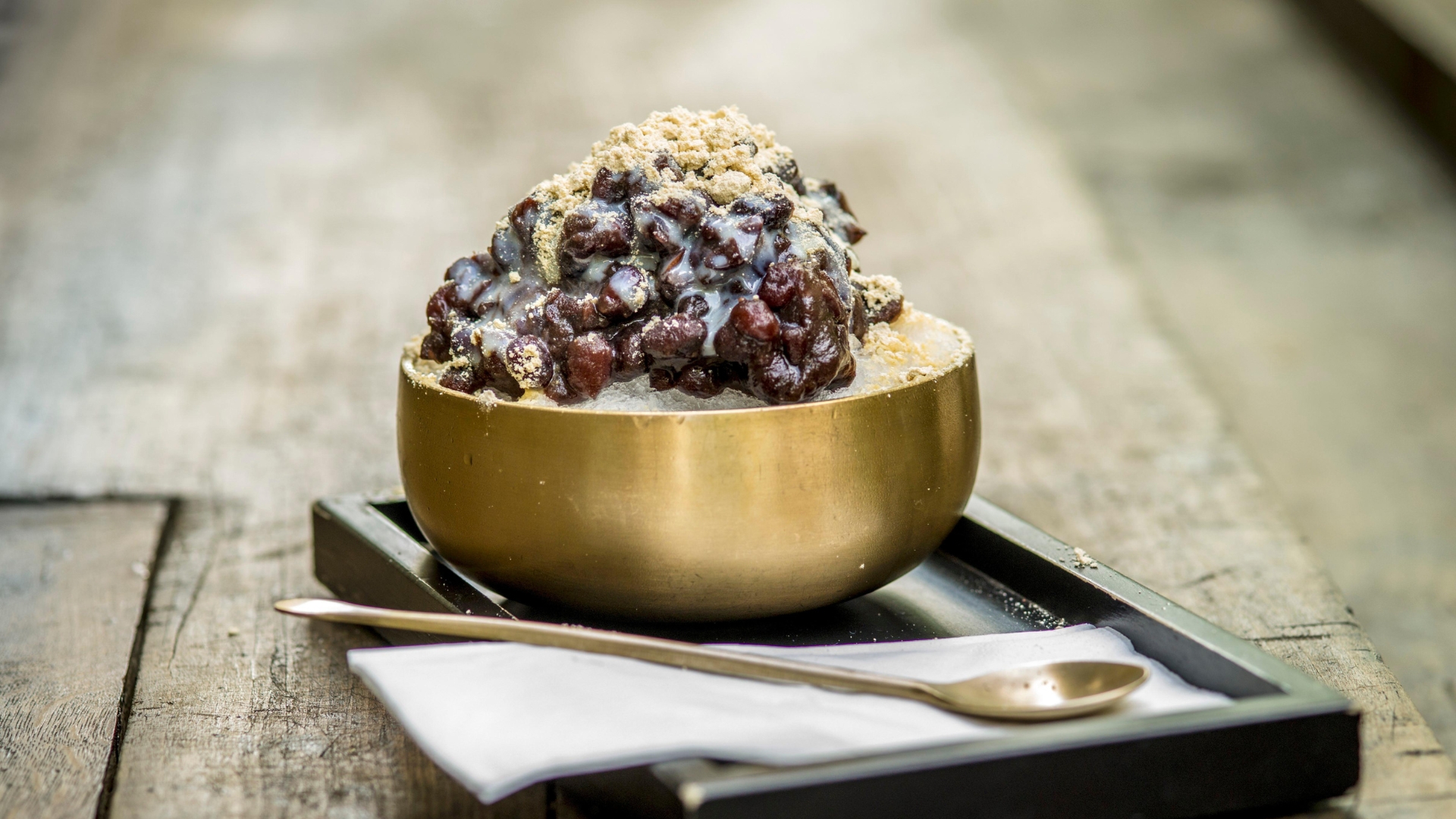 A golden spoon lies next to a matching gold bowl full of patbingsu