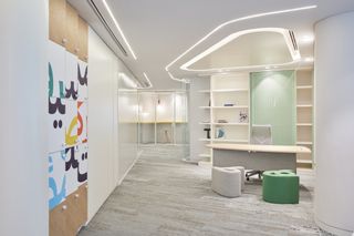 Office space interior with muted colour palette. On the left is a posted of colourful Arabic typography
