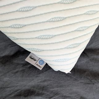 The Tempur Cloud SmartCool pillow being tested on a bed with grey linen covers