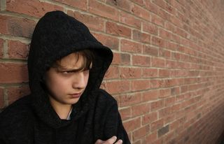 Depressed young teenage boy in a hoodie.