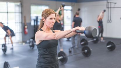 Do kettlebell swings work abs? Image shows woman in gym doing kettlebell swing