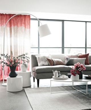 Grey living room ideas illustrated in a pale grey scheme with white coffee tables and pink drapes.