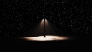 An artist&#039;s rendering of a streetlamp on a dark landscape with stars behind it