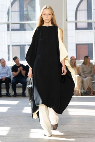 An S/S 25 model wearing a cape dress over pants at the Proenza Schouler show.