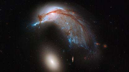 The birdlike galaxy NGC 2936 is being ripped apart by the smaller galaxy NGC 2937.