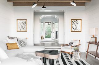 Horizontal white wood walls, black and white rugs, paintings, cushions, laps and rug
