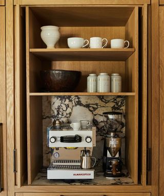 Coffee bar essentials in wooden hutch with decorated shelving, and chocolate brown tiling