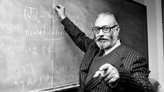 Black and white photo of Abdus Salam teaching at a blackboard.