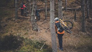 Mountain bikers carrying their bikes in forest